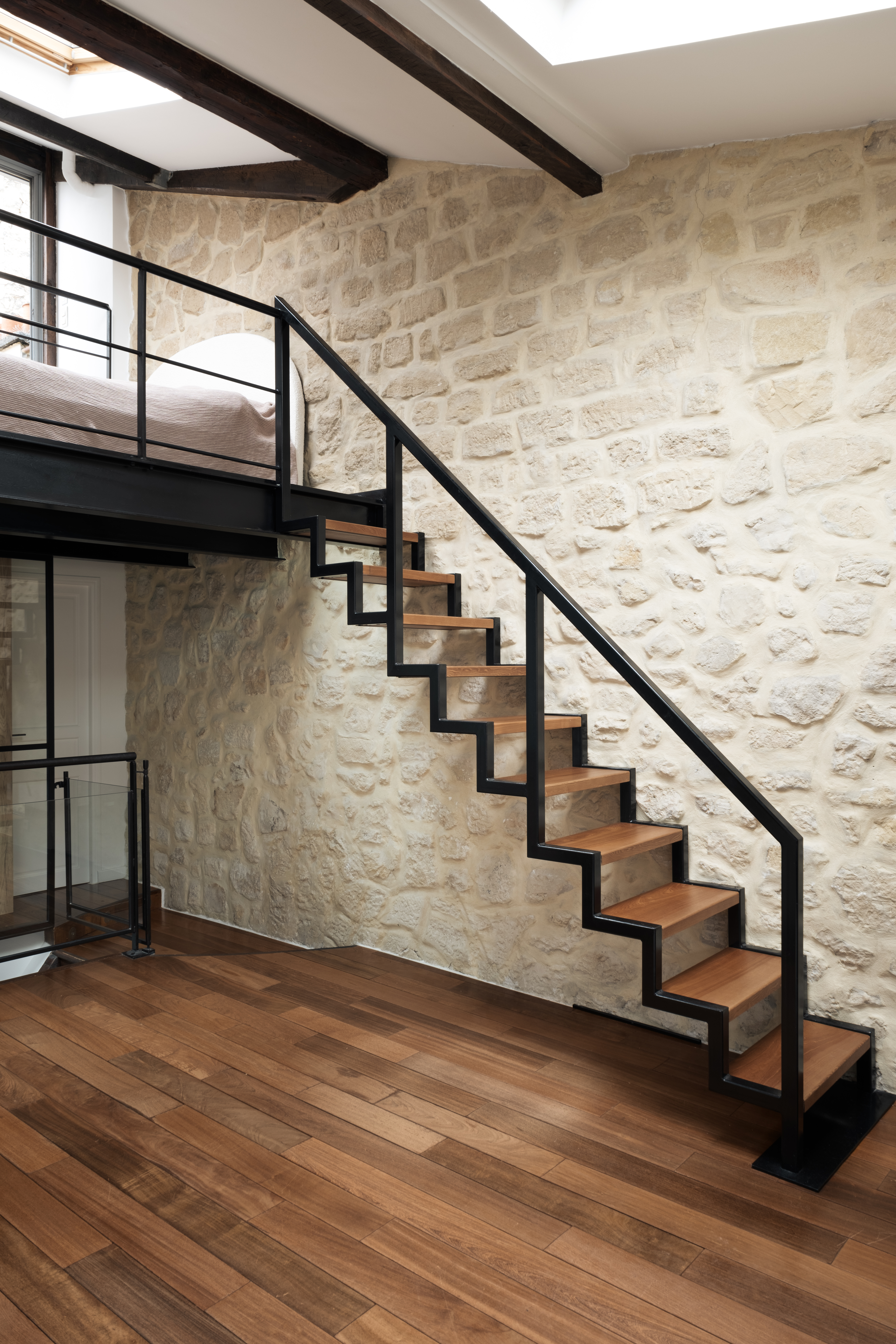 Mur porteur en pierre et poutre métallique apparente dans un appartement parisien rénové par HomeRev